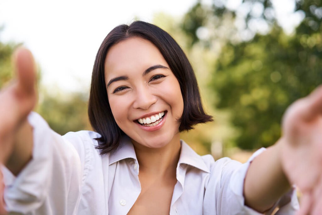 Smiling Asian Girl Takes Selfie Video Chats Holds Smartphone Speaks Camera Posing Park